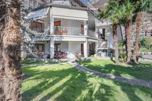 una casa con palmeras delante en Appartamento La Palma, en Darfo Boario Terme
