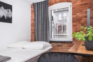 Bett in einem Zimmer mit Ziegelwand und Fenster in der Unterkunft Apartament Zwycięstwa in Gliwice