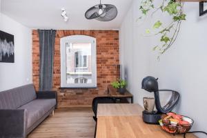 ein Wohnzimmer mit Sofa und Ziegelwand in der Unterkunft Apartament Zwycięstwa in Gliwice