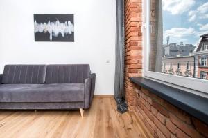 ein Sofa in einem Zimmer mit Fenster in der Unterkunft Apartament Zwycięstwa in Gliwice