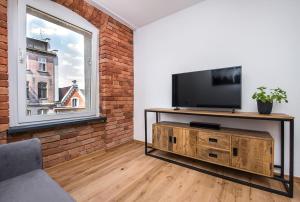a living room with a flat screen tv and a brick wall at Apartament Zwycięstwa in Gliwice