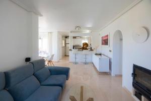 een woonkamer met een blauwe bank en een keuken bij Villa La Zenia in Orihuela