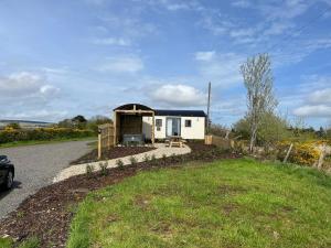 a tiny house with a porch on the side of a road at Redfox Shepherds hut and private hot tub in Ballynameen