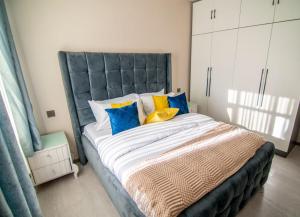 a bedroom with a large bed with colorful pillows at Lux Suites Royal Gardens Studio Apartments in Nairobi