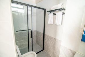 a bathroom with a shower with a toilet and towels at Lux Suites Royal Gardens Studio Apartments in Nairobi