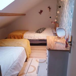 a small room with two beds and a mirror at Gîte de la Ferme du Clos Giot in Saint-Vaast-la-Hougue