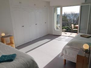 a white bedroom with two beds and a balcony at Les Balcons du Trégor in Lannion