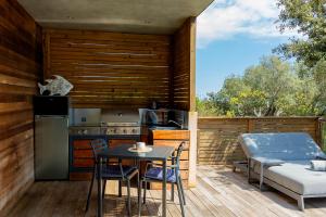 a patio with a table and a kitchen and a bed at SWIM LODGE HOTEL Piscine privée ou Jacuzzi privé in Porto-Vecchio