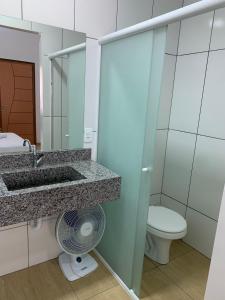 a bathroom with a sink and a toilet and a fan at HOTEL POUSADA POR DO SOL in Pato Branco