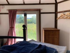 - une chambre avec un lit et une grande fenêtre dans l'établissement Lower Marsh Farm in Cornwall, à Saltash