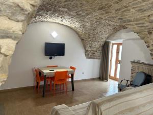 - un salon avec une table, des chaises et une télévision dans l'établissement La Tavernetta, à Pietra Montecorvino