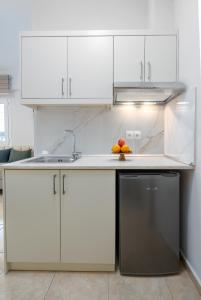 - une cuisine blanche avec un évier et un lave-vaisselle dans l'établissement GrecoInn Family Angela Rooms, à Leptokaryá