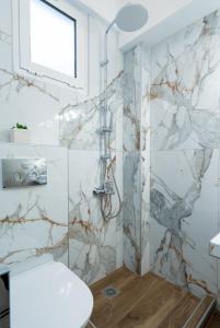 La salle de bains est pourvue d'une douche et de carrelage en marbre. dans l'établissement GrecoInn Family Angela Rooms, à Leptokaryá