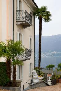 a building with a balcony and a palm tree at Boutique Hotel Villa Sarnia in San Nazzaro