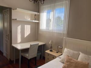 a bedroom with a desk and a bed and a window at HABITACION BAÑO COCINA JARDIN Y PARKING in Erandio