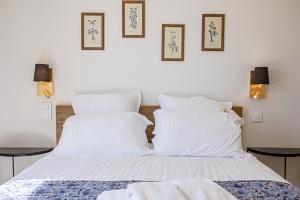 - une chambre avec 2 lits avec des draps blancs et des photos sur le mur dans l'établissement Domaine de l'auberderie Tropezienne, au Plan-de-la-Tour