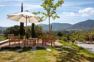 un patio con bancos, sombrilla y montañas en Domaine de l'auberderie Tropezienne en Plan-de-la-Tour