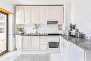 a white kitchen with white cabinets and a sink at Downtown Poet´s Apartment in Faro