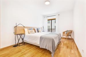 a white bedroom with a bed and a chair at Downtown Poet´s Apartment in Faro
