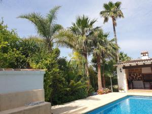a swimming pool with palm trees and a house at Casa Juanita in Montgo