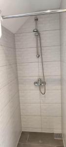 a shower in a bathroom with white tiles at Gościniec Mazurek in Giżycko