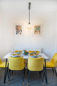 a dining room with a table and yellow chairs at Spacious 3 bed house w/ garden, parking, WiFi, TV in Coventry