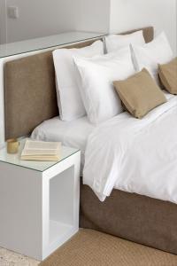 a bed with white pillows and a book on a table at Aura Homes, Contemporary Apartments in Central Athens in Athens