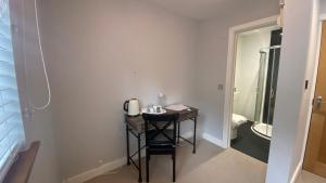 a small table in a room with a bathroom at Deepcut Lodge Bed & Breakfast in Camberley