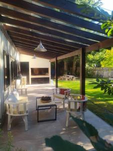 un patio avec des chaises et des tables sous une pergola dans l'établissement Villa La Angostura - El Encuentro: Un lugar soñado, à Villa La Angostura
