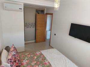 een slaapkamer met een bed en een flatscreen-tv bij BLANCA BEACH SIDI RAHAL in Sidi Rahal