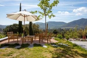 patio z ławkami i parasolem oraz góry w obiekcie Domaine de l'auberderie Esterel w mieście Le Plan-de-la-Tour