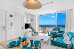 - un salon avec une table et une vue sur l'océan dans l'établissement MEDANO4YOU The First Line Sea View Penthouse, à El Médano