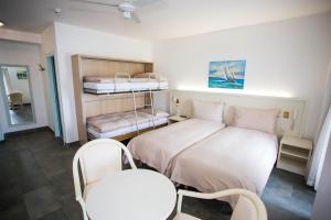 ヴィルヌーヴにあるオテル デュ ポールのベッド2台、テーブル、椅子が備わる小さな客室です。
