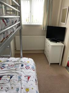 a bedroom with a bunk bed and a television at Hot Tub Beach Bungalow - free parking & child friendly in South Hayling