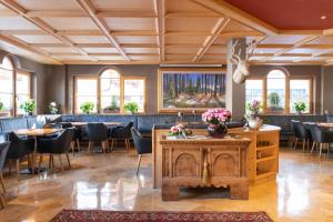 una sala da pranzo con tavoli, sedie e finestre di Hotel Somont a Selva di Val Gardena