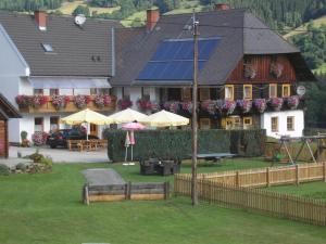 a house with a yard with tables and umbrellas at Pension Edlinger in Sankt Georgen ob Murau
