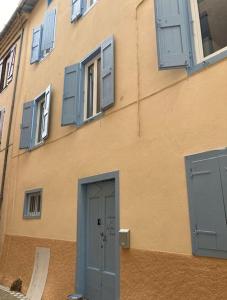 un edificio con ventanas con persianas azules y una puerta en Maison Centrale, en Ax-les-Thermes