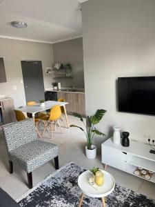 a living room with a television and a table and chairs at Blue Lilly - 50 on Lever Unit 19 in Midrand