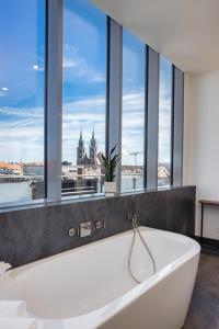a white bath tub in a bathroom with windows at Luxus Penthouse über den Dächern von Nürnberg in Nuremberg