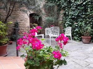 a patio with white chairs and pink flowers at Casa Rural Erletxe in Laguardia