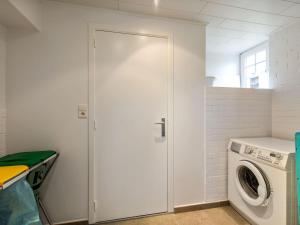 eine weiße Tür in einer Waschküche mit Waschmaschine in der Unterkunft Renovated Hortensia Villa with a unique location next to the dunes in Koksijde