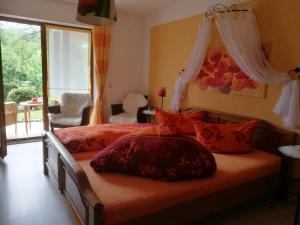 Schlafzimmer mit einem Bett mit roten Kissen und einem Fenster in der Unterkunft Wohlfühlgästehaus Eva-Maria Schätzle in Schonach