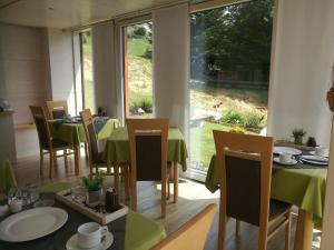 ein Restaurant mit Tischen und Stühlen und einem großen Fenster in der Unterkunft Wohlfühlgästehaus Eva-Maria Schätzle in Schonach