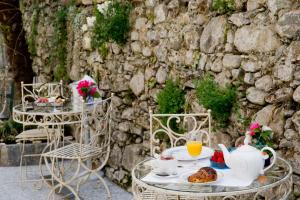 a table with tea and biscuits on it next to a stone wall at Boutique Hotel Villa Sarnia in San Nazzaro