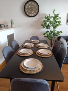 einem schwarzen Tisch mit Tellern und Stühlen und einer Uhr in der Unterkunft T3 Lumineux - Berges de la Garonne - Parking in Toulouse