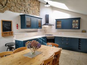 a kitchen with blue cabinets and a wooden table at Trethellan View in Stithians