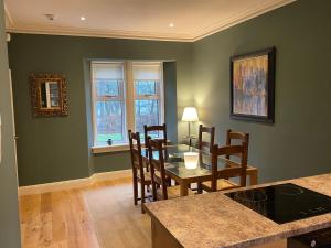 Luxury Garden Cottage في Dalry: غرفة طعام بجدران خضراء وطاولة وكراسي