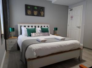 1 dormitorio con 1 cama grande con almohadas verdes en Kingdom Lodge, en Killarney