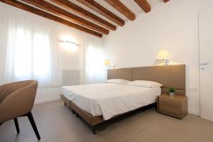 a bedroom with a white bed and a chair at Residence degli Artisti in Venice