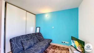 ein Wohnzimmer mit einem Sofa und einer blauen Wand in der Unterkunft Anjou 1 - studio de 20 m2 à Saint-Denis in Saint-Denis